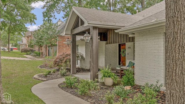 803 Fairway Dr, Jonesboro, AR 72401 - property entrance with board and batten siding, a lawn, roof with shingles, brick siding, and a chimney