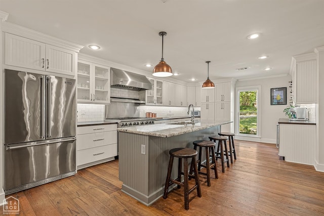 803 Fairway Dr, Jonesboro, AR 72401 - kitchen featuring dark wood-type flooring, tasteful backsplash, wall chimney range hood, appliances with stainless steel finishes, and a sink