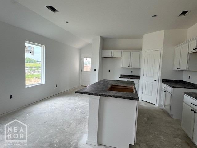 5702 Crockett Dr, Jonesboro, AR 72404 - kitchen with a center island, lofted ceiling, dark countertops, and white cabinetry