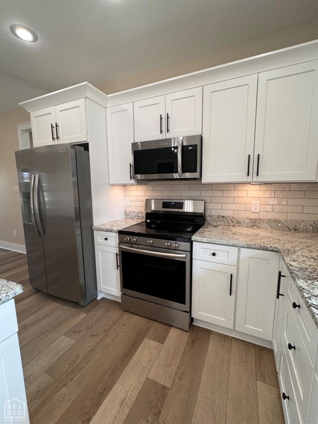 100 Lenford Dr, Bono, AR 72416 - kitchen with appliances with stainless steel finishes, light wood-type flooring, white cabinetry, backsplash, and recessed lighting