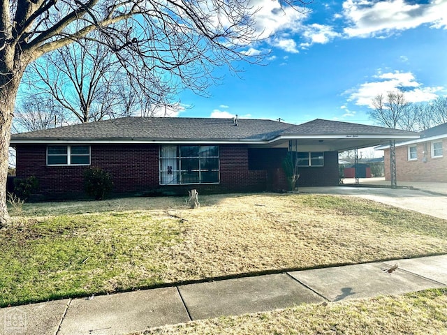 single story home featuring brick siding, a front yard, driveway, and a carport