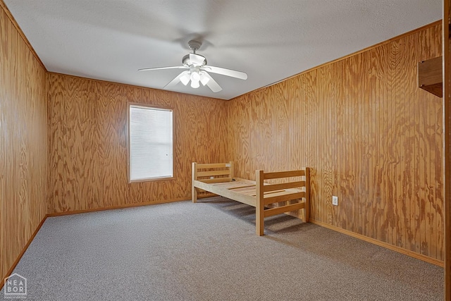 unfurnished bedroom featuring carpet, wooden walls, and a textured ceiling