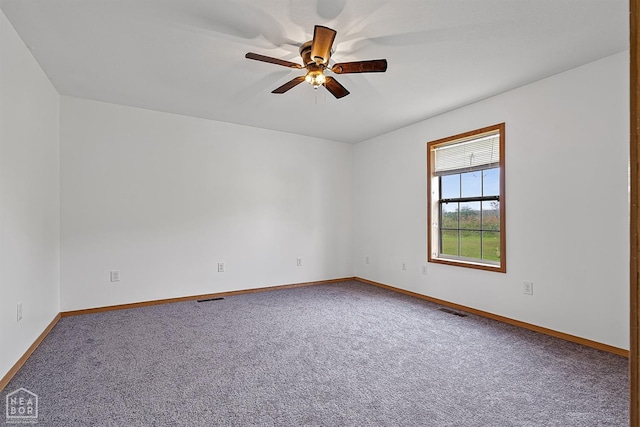 spare room featuring carpet, visible vents, a ceiling fan, and baseboards