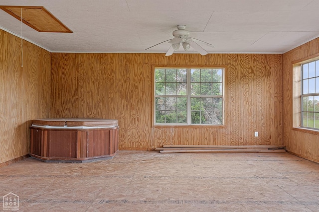 spare room with baseboards, wood walls, ceiling fan, and a baseboard heating unit