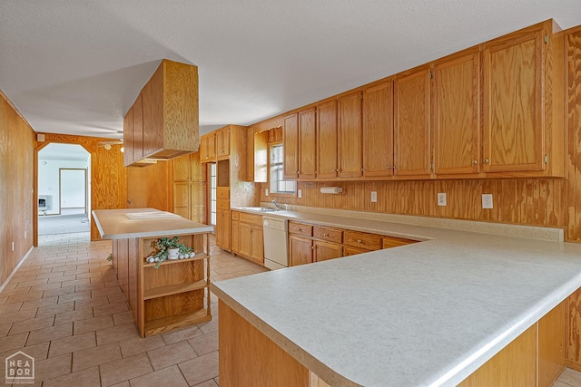 kitchen featuring a sink, white dishwasher, open shelves, a peninsula, and light countertops