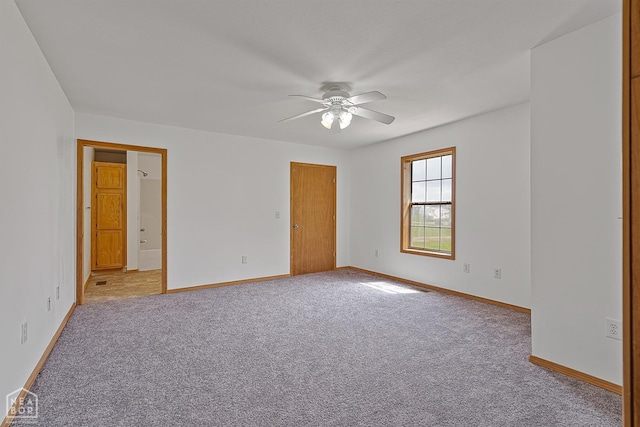 unfurnished room featuring light colored carpet, a ceiling fan, and baseboards