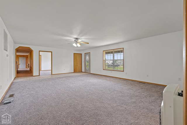 interior space with a ceiling fan, visible vents, light colored carpet, and baseboards