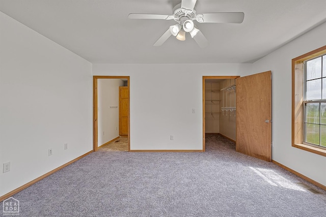 unfurnished bedroom featuring a closet, ceiling fan, baseboards, carpet floors, and a spacious closet
