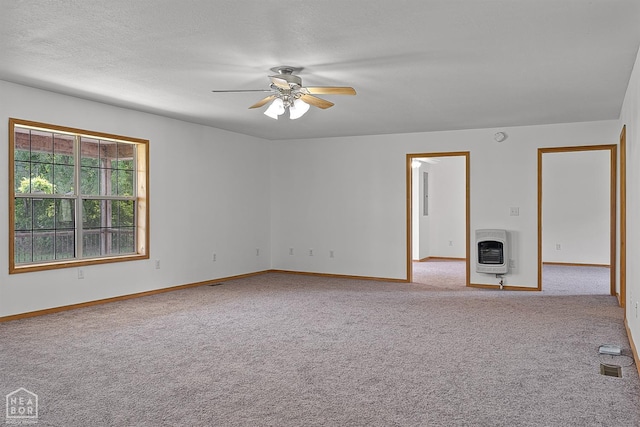 carpeted empty room featuring heating unit, a ceiling fan, and baseboards