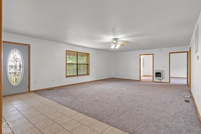 interior space featuring heating unit, a ceiling fan, light carpet, and baseboards