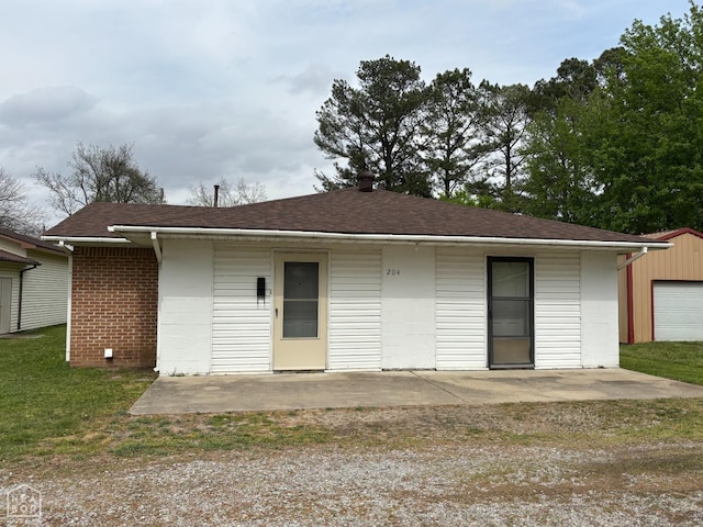 rear view of property featuring a shingled roof, a patio area, and a yard