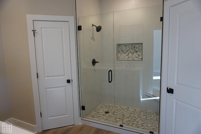 full bath featuring wood finished floors and a shower stall