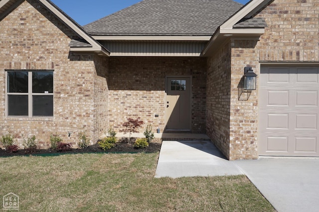 entrance to property with a yard, roof with shingles, brick siding, and a garage