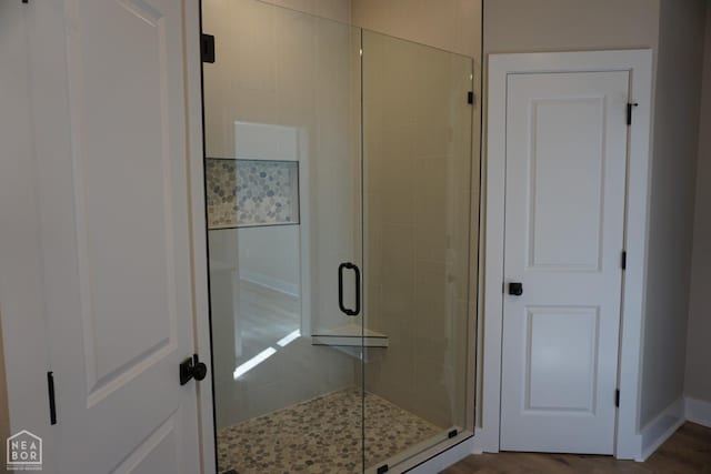 bathroom featuring wood finished floors, baseboards, and a stall shower