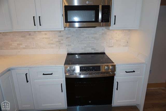 kitchen featuring stainless steel appliances, wood finished floors, decorative backsplash, and white cabinets