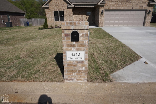 view of front of home featuring brick siding, driveway, a garage, a front yard, and cooling unit