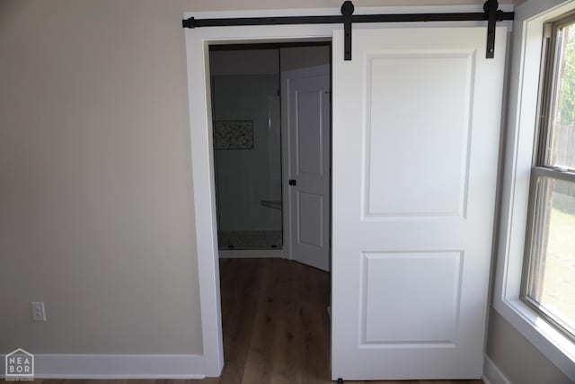 hallway featuring a barn door and wood finished floors