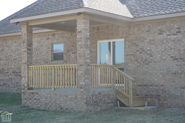 exterior space featuring brick siding and roof with shingles
