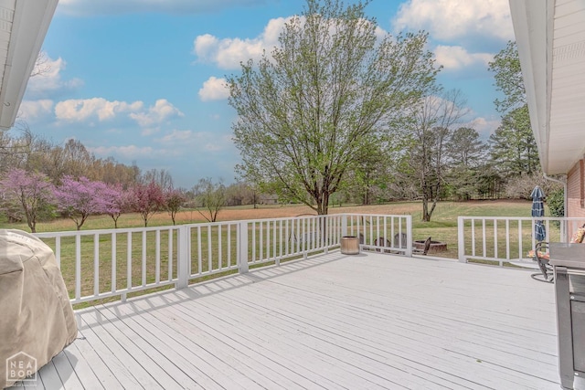 wooden deck with a grill and a lawn