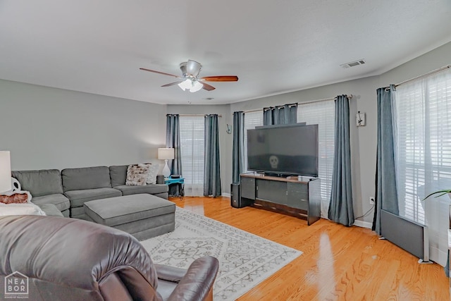 living area with wood finished floors, a ceiling fan, visible vents, and plenty of natural light