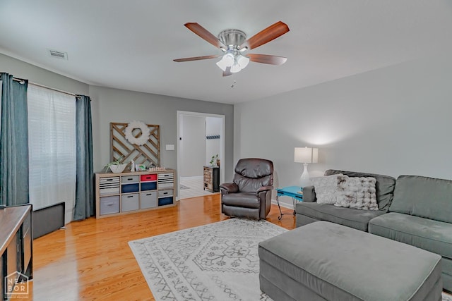 living room featuring light wood-type flooring, a ceiling fan, and visible vents