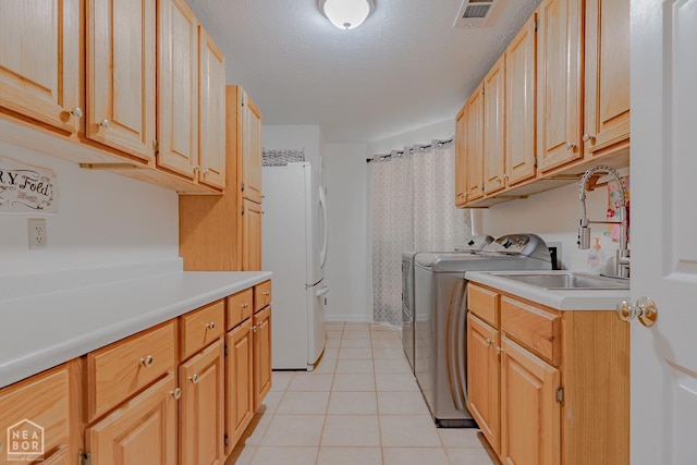 washroom with visible vents, light tile patterned flooring, a sink, washer and dryer, and cabinet space