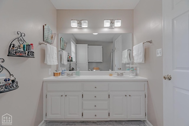 bathroom featuring double vanity, a sink, and baseboards