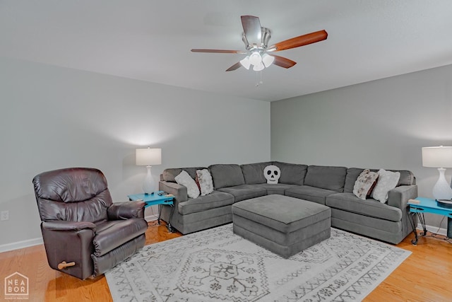 living room featuring light wood-style floors, baseboards, and ceiling fan