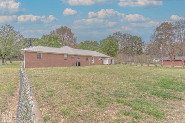 view of yard featuring a storage shed, fence, and an outbuilding