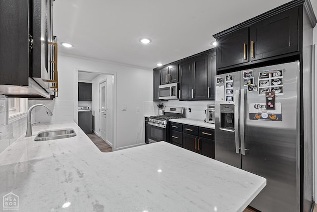 608 Finch Ave, Monette, AR 72447 - kitchen featuring appliances with stainless steel finishes, dark cabinetry, washer / dryer, light stone countertops, and recessed lighting