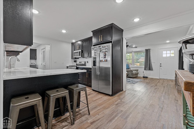 608 Finch Ave, Monette, AR 72447 - kitchen with stainless steel appliances, a sink, light wood finished floors, a breakfast bar area, and recessed lighting