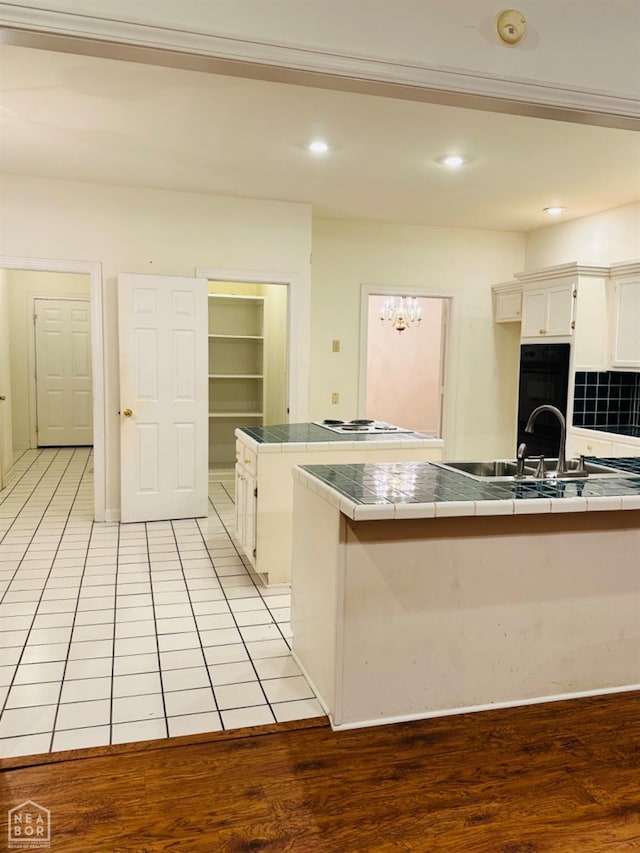 2208 John Cir, Newport, AR 72112 - kitchen with white cabinetry, tile countertops, an inviting chandelier, and black oven