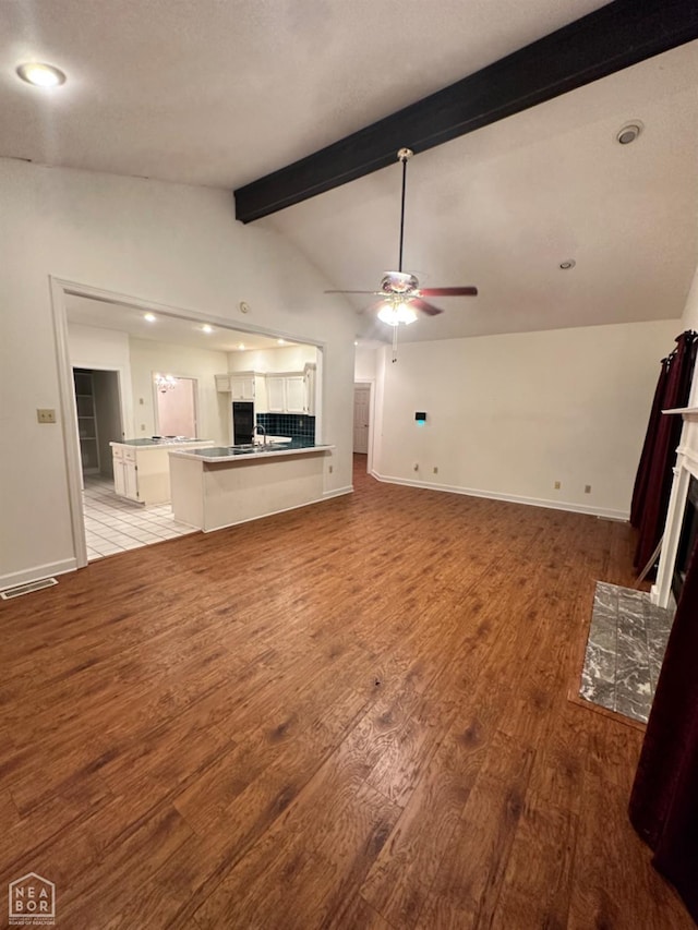 2208 John Cir, Newport, AR 72112 - unfurnished living room featuring baseboards, lofted ceiling with beams, ceiling fan, light wood finished floors, and a tile fireplace