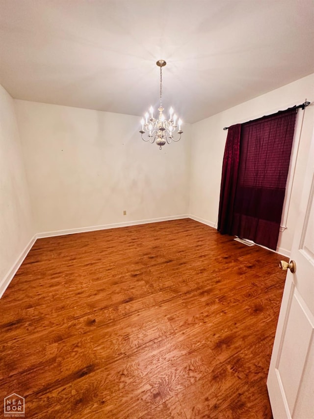 2208 John Cir, Newport, AR 72112 - unfurnished room with baseboards, an inviting chandelier, and wood finished floors