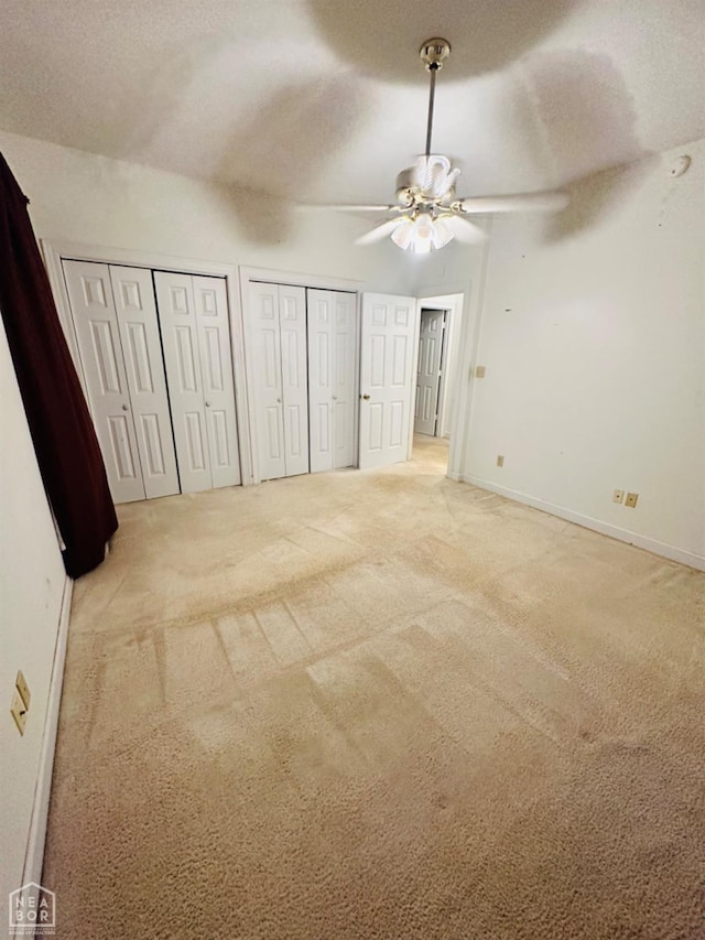 2208 John Cir, Newport, AR 72112 - unfurnished bedroom with baseboards, a textured ceiling, two closets, a ceiling fan, and carpet floors