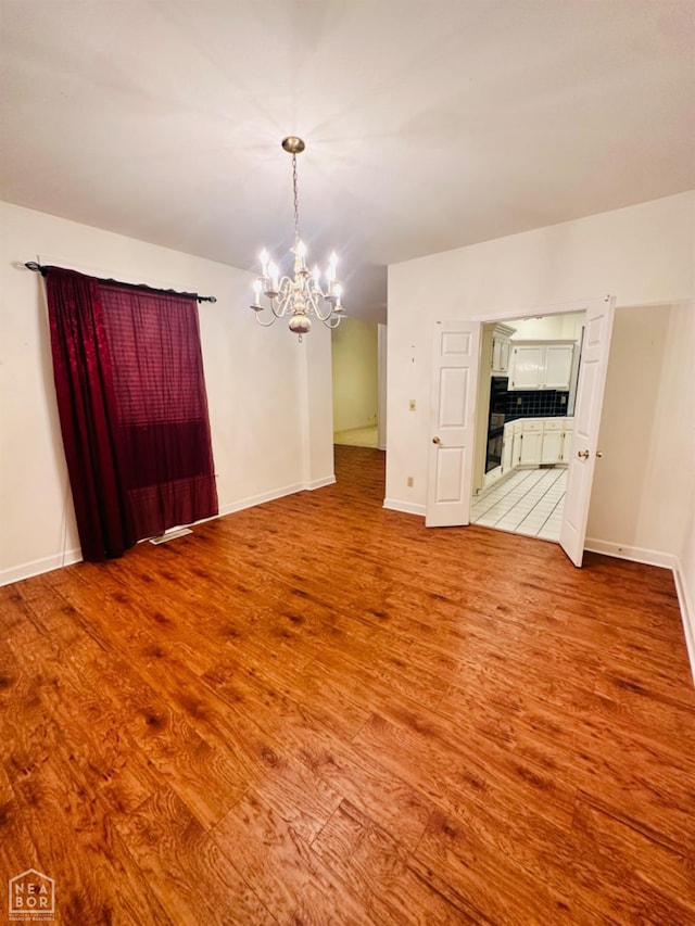 2208 John Cir, Newport, AR 72112 - unfurnished dining area featuring baseboards, light wood finished floors, and a notable chandelier