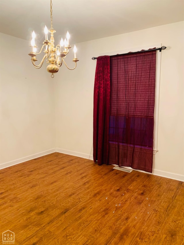 2208 John Cir, Newport, AR 72112 - unfurnished room with a chandelier, visible vents, baseboards, and wood finished floors