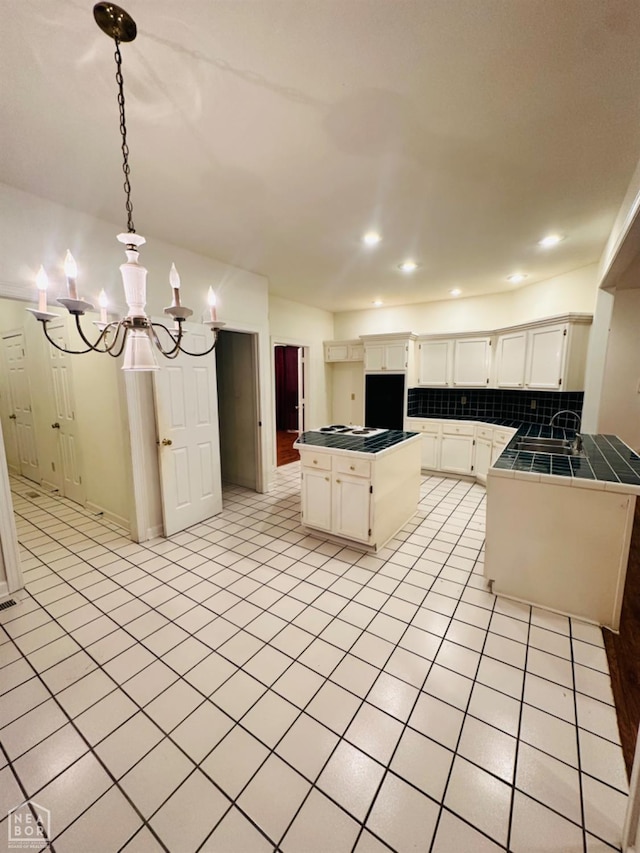 2208 John Cir, Newport, AR 72112 - kitchen featuring a chandelier, a center island, white cabinetry, backsplash, and tile countertops