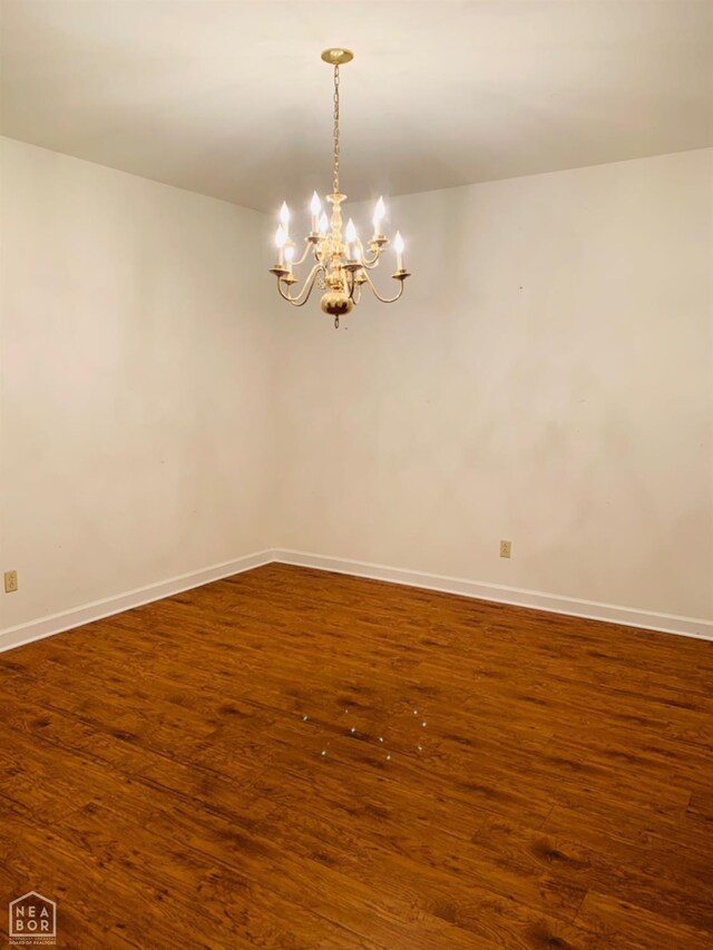 2208 John Cir, Newport, AR 72112 - unfurnished room featuring baseboards, an inviting chandelier, and wood finished floors
