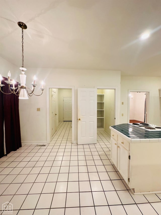 2208 John Cir, Newport, AR 72112 - kitchen featuring light tile patterned floors, white cabinets, baseboards, a chandelier, and tile countertops
