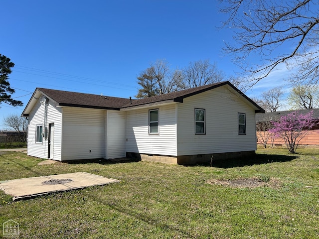 rear view of house with crawl space, a shingled roof, and a lawn
