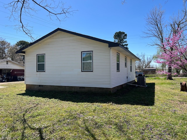 view of side of property featuring crawl space, central AC, and a lawn