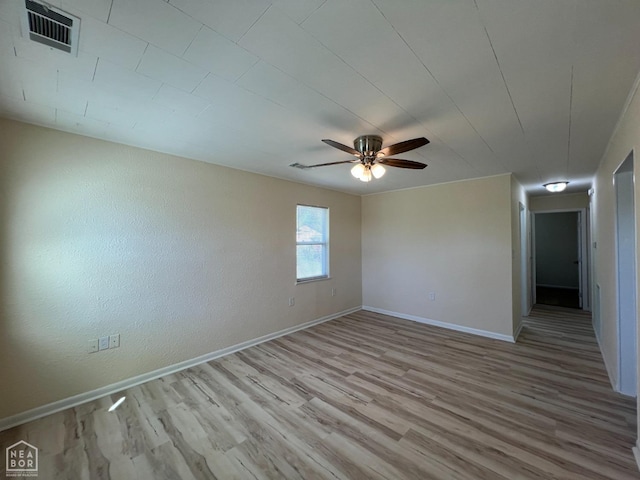 spare room featuring light wood-type flooring, ceiling fan, baseboards, and visible vents