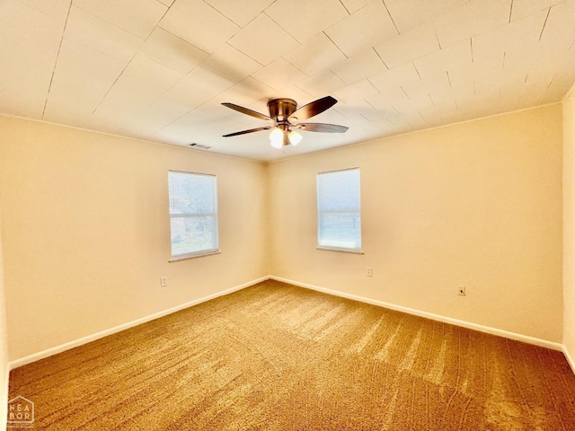 carpeted empty room featuring baseboards, a ceiling fan, and visible vents