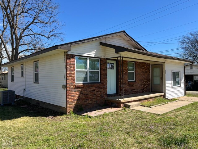 view of front of home featuring a front yard, brick siding, and central AC