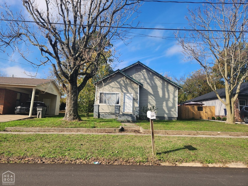 bungalow-style house featuring an attached carport and a front lawn