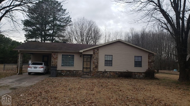 view of front of home featuring stone siding, an attached carport, and driveway