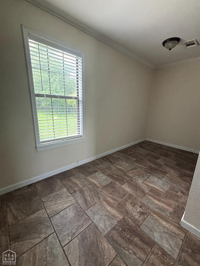 empty room with baseboards, visible vents, crown molding, and stone finish floor