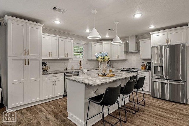 4328 Lynx Ln, Jonesboro, AR 72405 - kitchen with appliances with stainless steel finishes, wall chimney exhaust hood, dark wood-type flooring, decorative backsplash, and white cabinetry