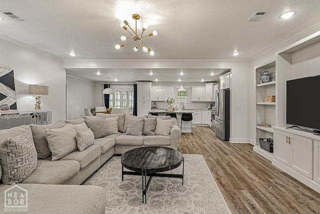 4328 Lynx Ln, Jonesboro, AR 72405 - living room with crown molding, light wood-type flooring, a textured ceiling, a chandelier, and built in shelves